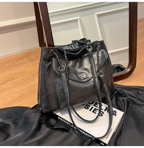 Dettaglio borsa tote in pelle nera con chiusura a scatto argento su velluto