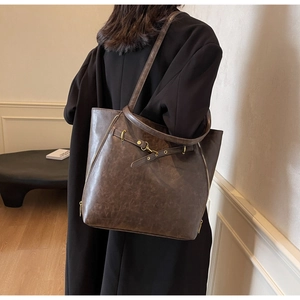 Detail of dark brown vintage leather tote bag with gold ring buckle and side zipper
