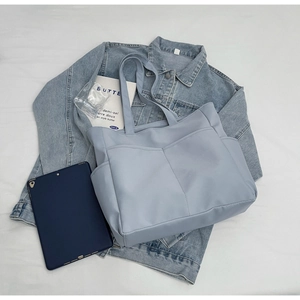 Sac cabas en toile bleu clair avec poches multiples sur fond blanc avec tablette