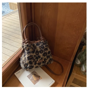 Dettaglio borsa a secchiello leopardata in pelliccia sintetica con manici in pelle marrone