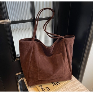 Close-up of deep brown suede tote bag with front pocket and elegant shoulder straps