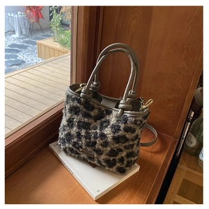 Dettaglio della borsa in peluche leopardata con manici in pelle grigia e fibbie dorate