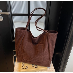 Detail of a large coffee brown faux suede tote bag featuring a practical outer pocket