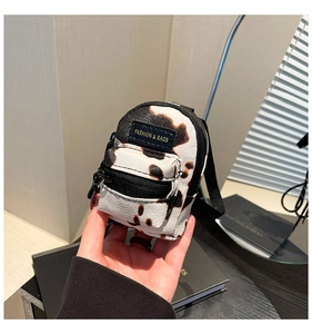 Detailed macro view of a mini cow print crossbody bag with fashion label and small zipper