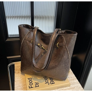 Macro detail of vintage brown tote bag featuring metallic zippers and retro buckle straps