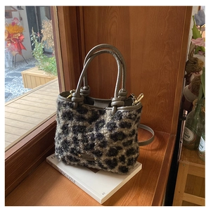 Dettaglio della borsa in peluche leopardata con manico in pelle e logo in metallo