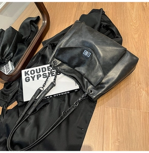 Dettaglio borsa shopper in pelle nera con catena in metallo e chiusura a girello quadrata