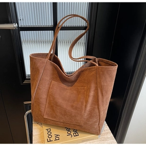 Macro detail of the brown suede tote bag featuring a square front pocket and minimalist strap