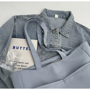 Vue à plat du sac fourre-tout en toile bleu clair avec bandoulière et accessoires épurés