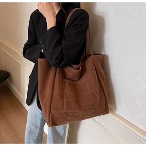Detail of a large brown suede tote bag featuring a practical square front pocket