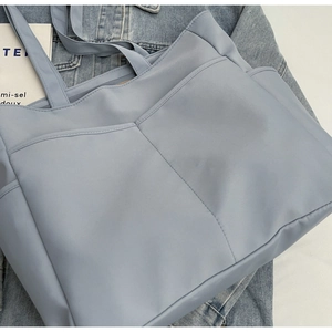Détail du cabas bleu montrant deux poches avant et une texture en nylon résistante