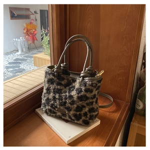 Dettaglio della borsa leopardata in peluche con manici in pelle marrone e placca logo oro