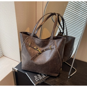 Detail view of a vintage dark brown tote bag with metal buckles and leather straps