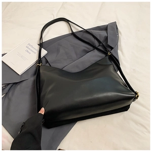 Detail of minimalist black tote bag with slender straps and vintage gold hardware accents