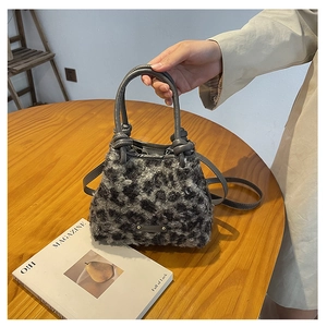 Dettaglio borsa a secchiello leopardata con manico in pelle annodato e logo in metallo