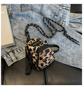 Detailed view of mini leopard print crossbody bag on denim and leather background
