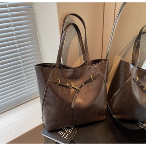 Detailed close-up of dark brown vintage leather tote with metal buckle and side zipper