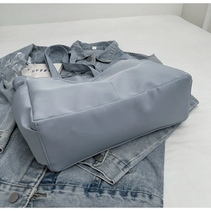 Sac fourre-tout en nylon bleu clair placé sur une veste en jean au style épuré
