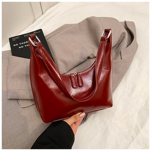 Dettaglio di una borsa in pelle verniciata rosso scuro con doppie cerniere in argento