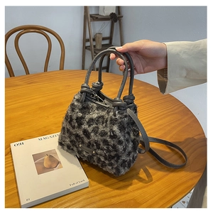 Dettaglio della borsa a secchiello leopardata in peluche con manici in pelle e logo in metallo