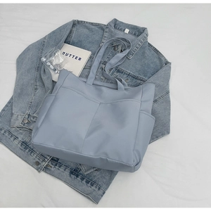 Détail du sac cabas en nylon bleu clair avec plusieurs poches frontales et grand volume