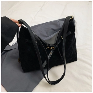 Detailed macro view of black suede tote bag with premium golden metal buckles and hardware