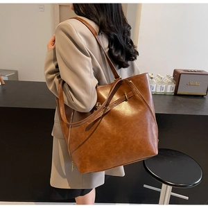 Detail view of brown PU leather tote bag with zipper decor on minimalist background