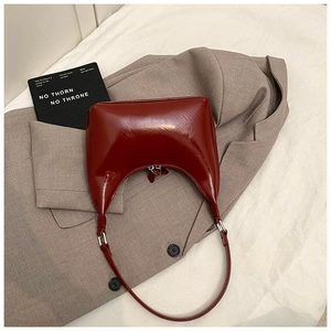 Dettaglio borsa hobo in vernice rosso scuro lucida su una giacca grigia da completo