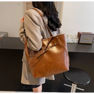 Detail of vintage brown leather tote bag with side zipper and adjustable shoulder strap