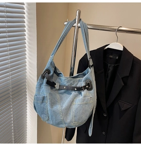 Detail der blauen Denim-Tragetasche mit Patchwork-Design und dekorativem schwarzen Ledergürtel