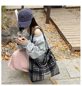 Outdoor shot showing the large capacity and draping of the black and white plaid tote bag