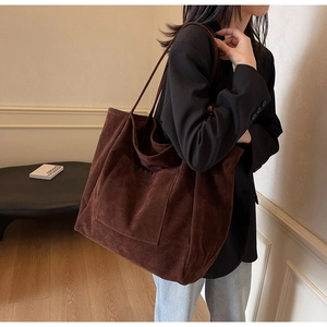 Detail shot of large brown faux suede tote bag with front pocket and slim shoulder straps