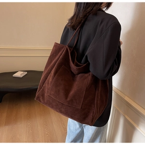 Detail of large brown suede tote bag with front pocket showing soft matte texture and room