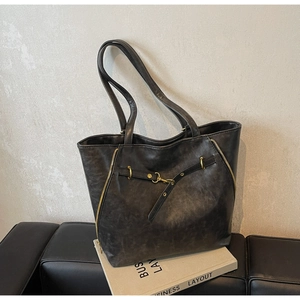 Detail of vintage textured tote bag featuring gold zippers and metallic buckle accents