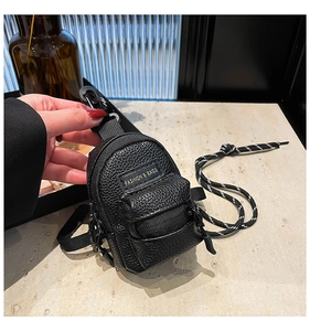 Detail of black mini crossbody bag charm with gold text and lychee pattern leather