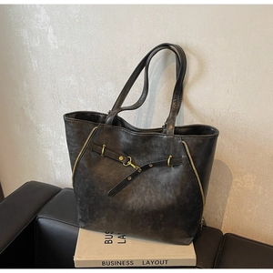 Detailed macro view of vintage charcoal grey tote bag with side zippers and metal buckles