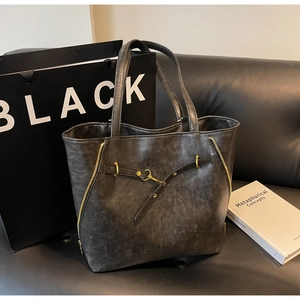 Detailed view of a charcoal grey vintage tote bag on a black leather sofa setup