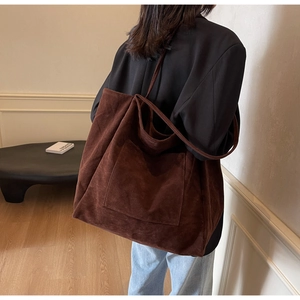 Detail of deep brown faux suede tote bag with large front pocket and long shoulder straps