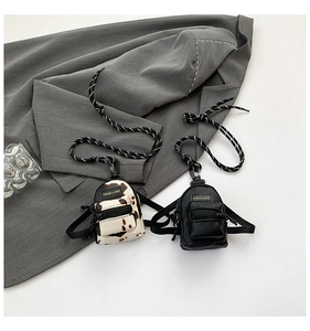 Mini cow print and black backpack charms with lanyards on a grey blazer background