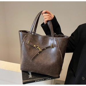 Detail of dark brown vintage leather tote with metal buckle and side zipper accents