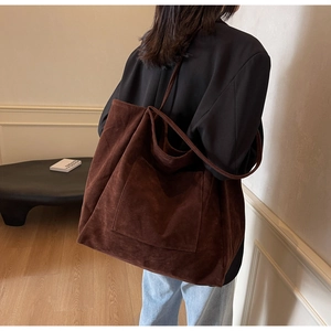 Detail view of the large capacity dark brown suede tote bag on a model's shoulder