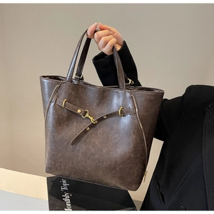 Close-up of deep coffee vintage tote bag featuring gold hardware and matte leather texture