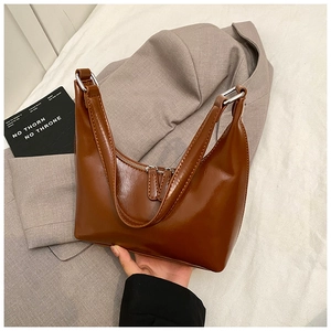 Dettaglio borsa in pelle lucida marrone con cerniere argentate e doppi manici curvi