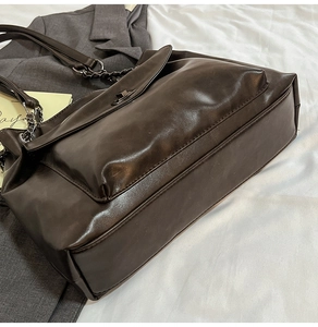 Vista dettagliata della borsa tote marrone scuro con catena metallica e chiusura a scatto