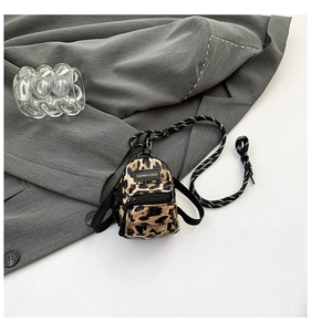 Close-up of mini leopard print crossbody bag with black leather label and striped cord