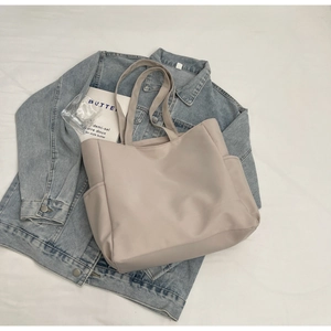 Vue détaillée du grand sac cabas en toile grise avec poches latérales sur jean