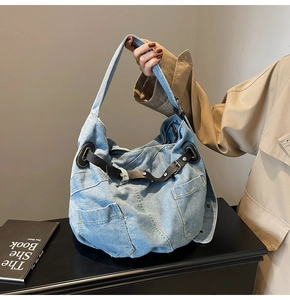 Detail der hellblauen Denim Hobo-Tasche mit schwarzen Lederriemen und Taschen