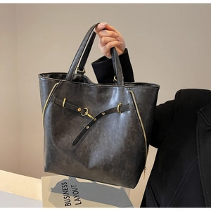 Detail of grey wax leather tote bag with functional gold zippers and buckle strap
