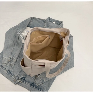 Détail de l'intérieur d'un sac cabas en toile beige avec poches zippées et doublure