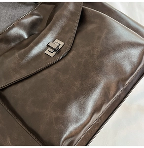 Dettaglio ravvicinato della borsa in pelle caffè scuro con texture vintage e chiusura in metallo